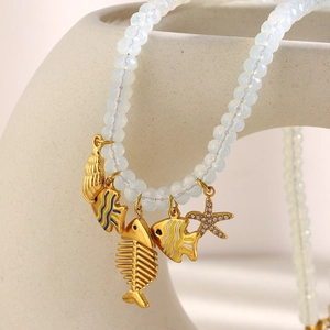 Détail de pendentifs arête de poisson et coquillage dorés 18K sur collier perlé