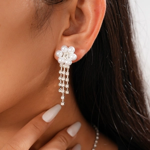Detailed view of silver flower earrings with white pearls and sparkling rhinestone tassels