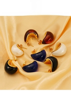 Detail of C-shaped titanium steel earrings in amber, pearl white, navy, and black colors