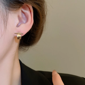 Close-up of minimalist gold geometric bar and U-shape earrings on a female model