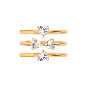 Detailed view of three stacked gold-plated rings featuring heart-cut clear stones