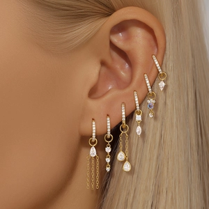 Close-up of golden S925 silver hoop earrings with rhombus zircon charms on a model