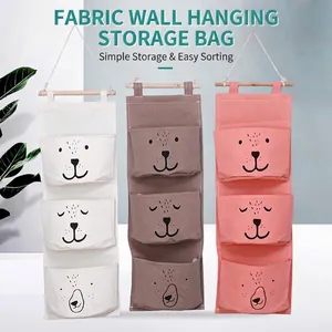 Three-pocket fabric wall hanging storage bags in white, brown, and pink with animal patterns