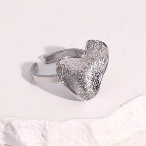 Close-up of silver heart ring with hand-hammered texture on white stone base