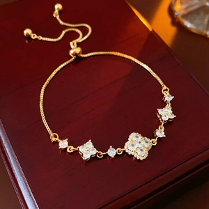Close-up of gold-plated clover bracelet with sparkling zircon stones on wood surface