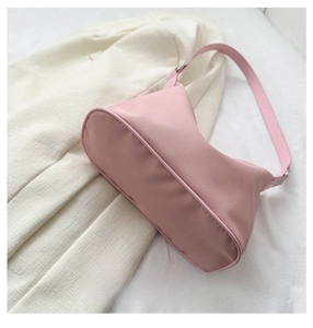 Detail of pink nylon shoulder bag with rounded bottom edges and silver metal buckle