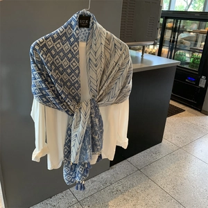 Blue and white patterned summer scarf with leaf prints and tassels on a mannequin