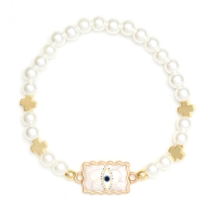 Macro detail of bead bracelet featuring white pearls, gold crosses and evil eye charm