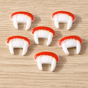 Flat lay of vampire fang resin charms for Halloween DIY crafts on wooden background