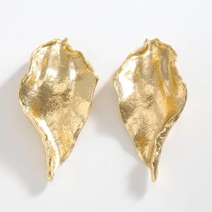 Detailed view of golden leaf earrings with irregular hammered metallic texture and shine