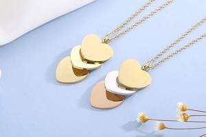 Vue à plat de colliers à pendentifs cœurs dorés et tricolores sur un tissu doux