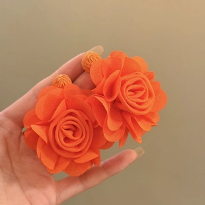 Close-up of vibrant orange chiffon fabric rose earrings showing delicate petal texture