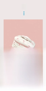 Détail d'une trousse de maquillage matelassée crème avec nœuds roses et poignée souple