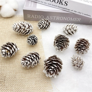 Natural pine cones with snowy white paint on rustic jute and soft velvet background