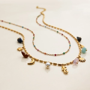Detail of layered gold necklace with seahorse charm, pearls and raw colorful gemstones