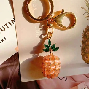 Close-up of pink opal pineapple keychain with gold-plated lobster clasp and green leaf detail