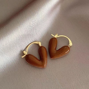 Detailed view of dark brown heart earrings with gold plating on a silk background