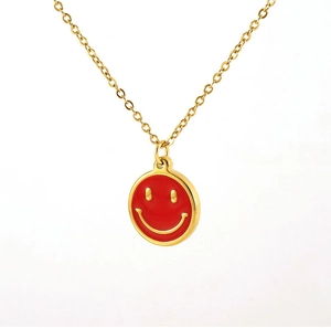 Gros plan d'un collier en acier inoxydable doré avec pendentif smiley en émail rouge