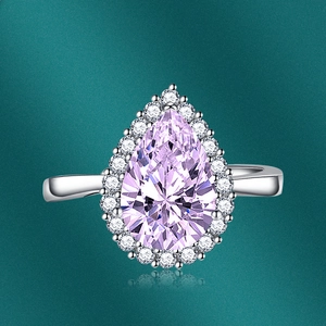 Close-up of pear-cut pink gemstone ring with halo diamond setting on silver band