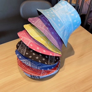 Stack of colorful paisley bandana bucket hats in various shades on wooden surface