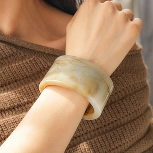 Detailed macro view of cream and brown marble pattern resin cuff bracelet on wrist