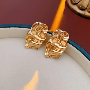 Macro view of gold irregular crinkle metal stud earrings on a jewelry box surface