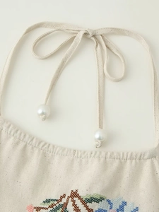 Détails de broderie florale au point de croix et perles sur le haut licou en lin beige