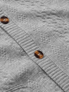 Detailed macro view of grey jacquard knit cardigan with marble pattern resin buttons