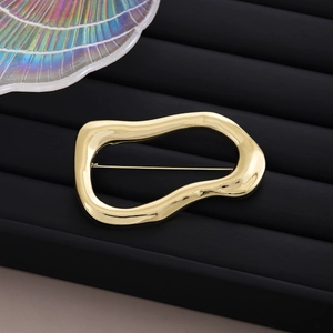 Macro detail of polished gold irregular brooch with secure pin back on black display