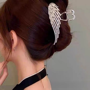Detail of silver angel wing hair claw clip with rhinestones and opal on dark hair