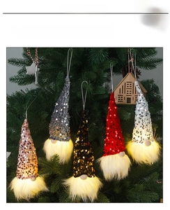 Macro detail of sequined Christmas gnome ornaments with warm glowing lights on a tree