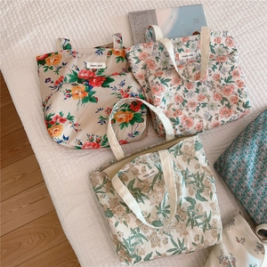 Detailed view of floral cotton tote bags with simple wish labels on a quilted surface