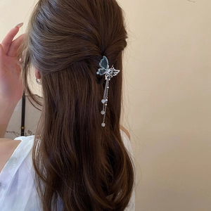 Détail d'une pince à cheveux papillon avec de longs glands métalliques et perles
