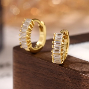 Macro shot of gold-plated huggie earrings with baguette-cut stones and secure clasp
