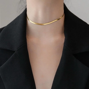 Elegant gold snake bone chain necklace for women worn with a dark suit jacket