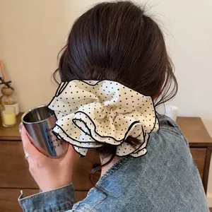 Polka dot oversized scrunchie with black trim shown on a ponytail in a soft home setting