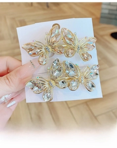 Detailed close-up of 3D crystal butterfly hair clips in champagne and white colors