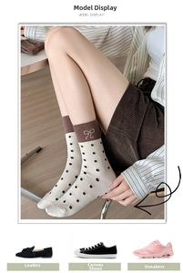 Close-up of cream knit socks with black polka dots, brown trim, and bow design details