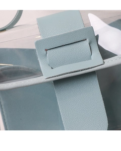 Detail of blue textured leather buckle and transparent PVC panel on a mini crossbody bag