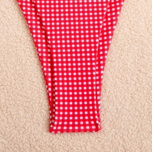 Macro detail of red and white gingham bikini bottom on soft white faux fur background