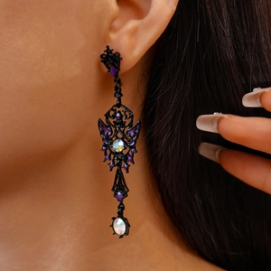 Close-up of gothic dark butterfly earring with purple rhinestones on a female model