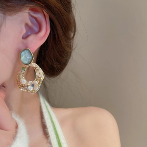 Detail view of vintage flower earring with teal gemstone, pearl and rhinestone inlay