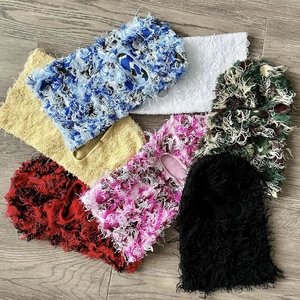 Multiple colorful distressed knit balaclavas with fringe detail on wooden background