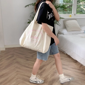 Lifestyle shot of large cream canvas tote bag with pink PARIS flower slogan embroidery