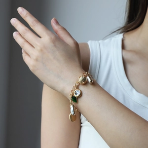 Vintage gold OT-buckle bracelet featuring green gems, shells, and baroque pearls