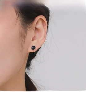 Close-up of elegant S925 sterling silver round black stone stud earrings on model