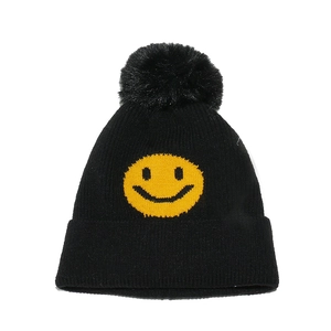 Detailed close-up of a black knit beanie featuring a fluffy pom-pom and yellow smiley face