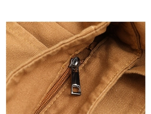 Detailed macro view of the metal zipper and washed canvas texture on a brown shoulder bag