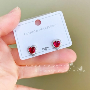 Detail of red heart ruby earrings with silver border and sparkling cubic zirconia halo