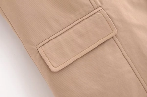 Dettaglio del gilet kaki che mostra la tasca con patta e la trama del tessuto